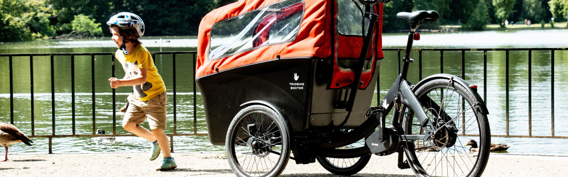 Ein Junge läuft vor dem Triobike Boxter Lastenfahrrad