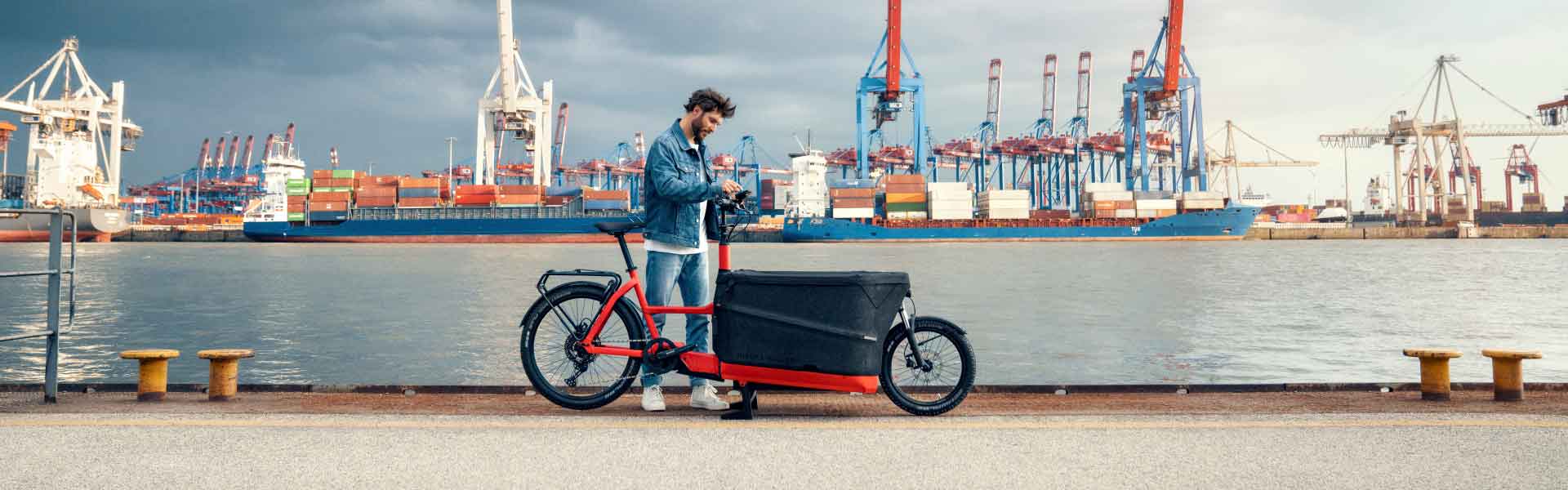 Ein Mann steht mit dem R&M Lastenrad am Hafen
