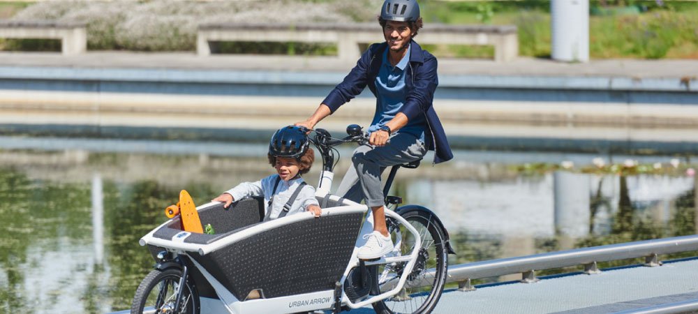 Mann fährt mit Sohn und seinem Urban Arrow über eine Brücke