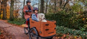 Frau fährt Babboe Go Lastenrad mit Kind und Hund