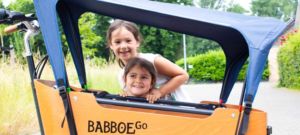 Zwei Mädchen gucken durch das Regenverdeck des Babboe Go Mountain
