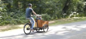 Mann fährt mit Babboe Go Mountain am Wald entlang