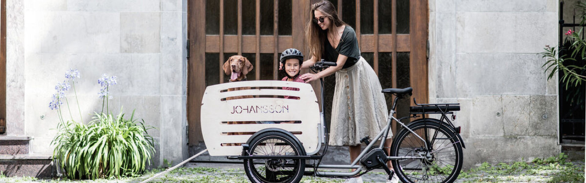 Eine Frau steht vor dem Johansson Lastenrad mit Hund und Kind