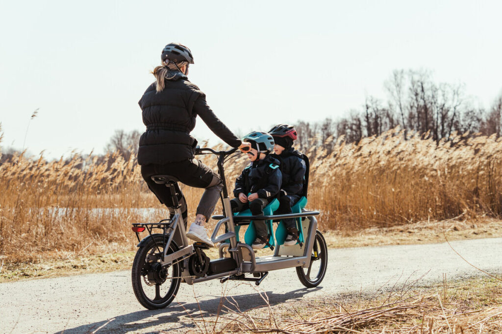 Frau fährt mit einem Lastenrad Gunnar und zwei Kindern