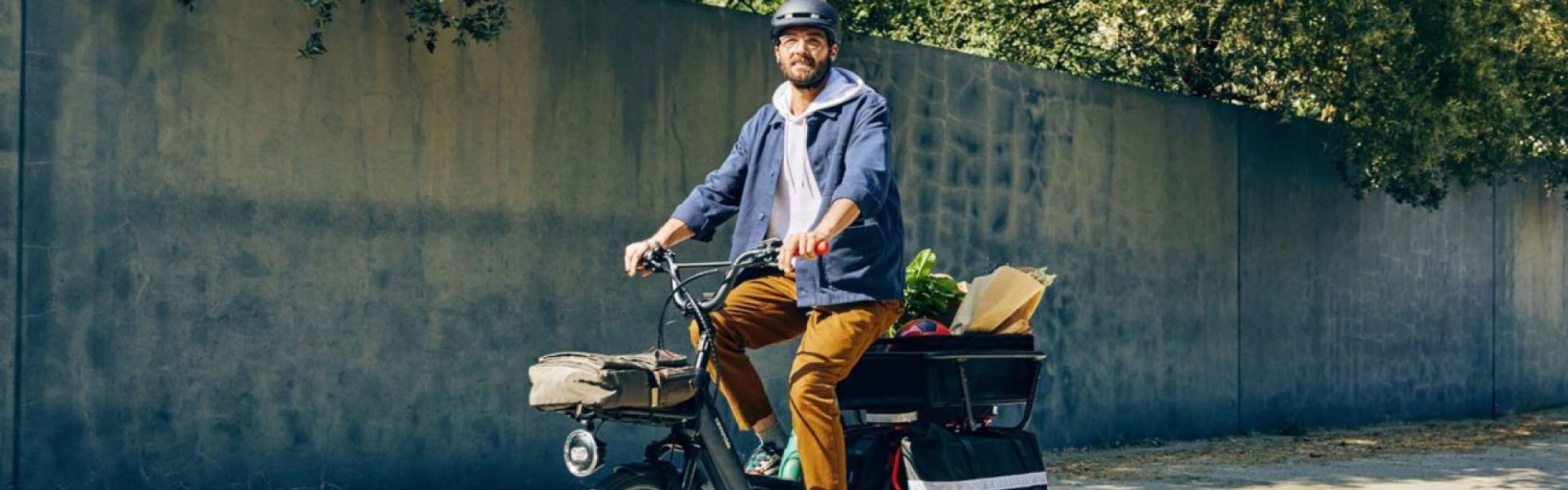Ein Mann fährt vollgepackt mit seinem Lastenrad von Cannondale die Straße entlang